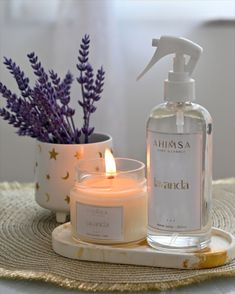 a bottle of lavender water next to a candle on a tray