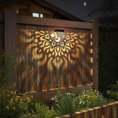 a wooden fence with a light shining on it and some flowers in the foreground