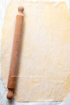 a rolling pin on top of a piece of parchment paper next to a wooden handle