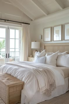 a large white bed sitting in a bedroom next to a window