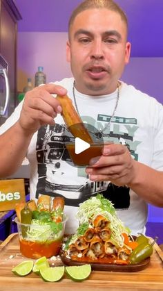 a man holding a hot dog in his hand while sitting at a table filled with food