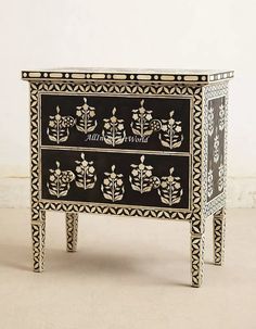 an ornate black and white chest of drawers