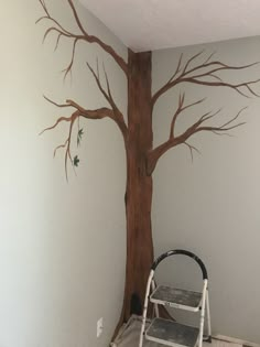 a ladder is sitting in front of a tree painted on the wall