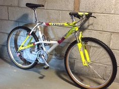 a yellow and white bike parked next to a brick wall