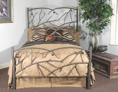 a bed with an iron frame and headboard is shown in front of a potted plant