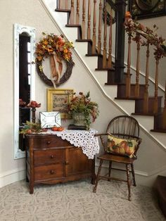 a wooden dresser sitting under a stair case next to a bannister filled with flowers