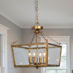 a chandelier hanging from the ceiling in a dining room with white walls and windows