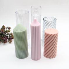 three different colored vases sitting next to each other on a white surface with flowers in the background