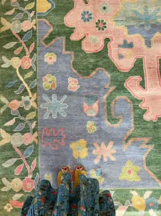 two pairs of shoes sitting on the ground in front of a colorful rug with flowers