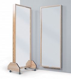 two mirrors are next to each other on casteors in front of a gray wall