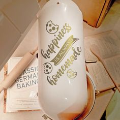 there is a bottle with some writing on it next to an open book and a rolling pin