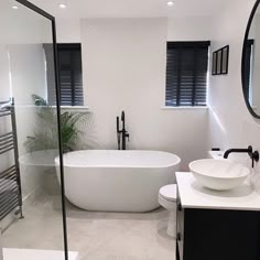 a white bath tub sitting next to a toilet under a bathroom mirror on top of a counter