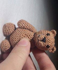 a hand holding a small crocheted teddy bear