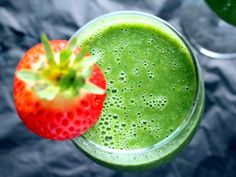 a green smoothie with a strawberry on the side