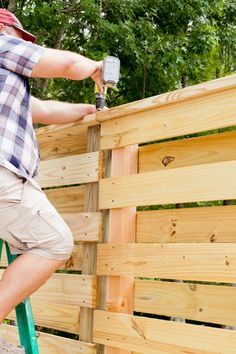 a man is painting the side of a wooden fence