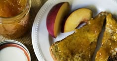 two pieces of toast on a plate with apples and honey next to it in a glass jar