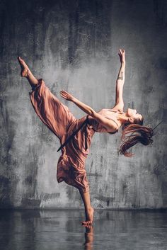 a woman is dancing in the middle of an artistic dance pose with her legs spread out