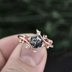 a person is holding an engagement ring with a black diamond in it's center