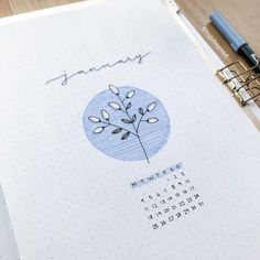 a calendar with a tree drawn on it and a pen next to it, sitting on top of a desk