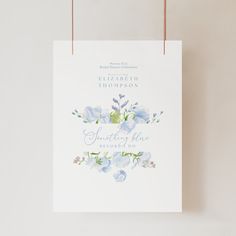 a white paper bag with blue flowers on it hanging from a string against a wall