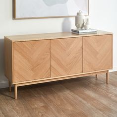 a wooden sideboard with two vases and a painting on the wall behind it