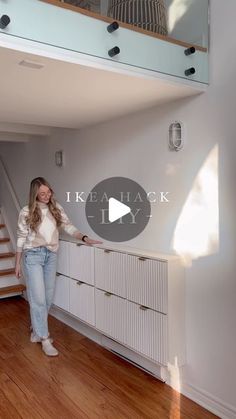 a woman is standing in the middle of a room with white walls and wooden floors