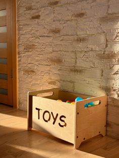 a toy box sitting on the floor in front of a brick wall that says toys