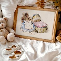 two stuffed animals sitting next to a framed painting on a bed with a teddy bear