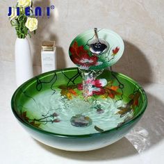 a bowl shaped sink with flowers painted on the bottom and water running from it's faucet