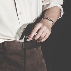 a man in a white shirt and brown pants is holding his hand on his belt