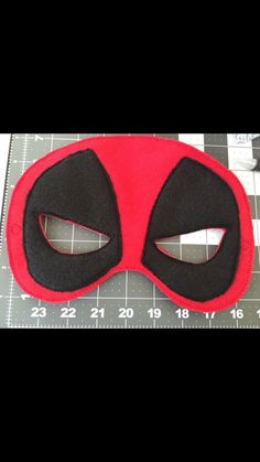 a red and black mask sitting on top of a ruler