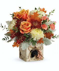 an arrangement of autumn flowers in a square vase