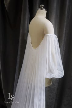 a mannequin wearing a white dress with long sleeves