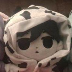 a close up of a stuffed animal wearing a cow print blanket on top of a bed