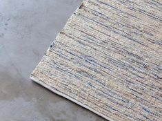 an area rug with blue and beige stripes on it, laying on concrete flooring