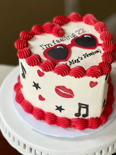 a red and white birthday cake decorated with music notes, heart - shaped sunglasses and lipstick