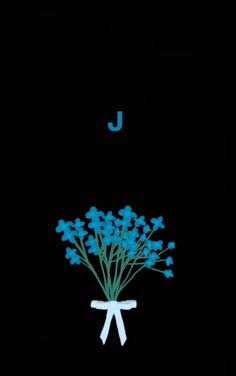 a bouquet of blue flowers sitting on top of a black background with the letter j