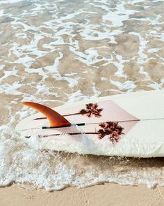 a surfboard laying on top of the sand near the ocean water at the beach