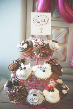 cupcakes are arranged on a pink stand with a sign that says pup cakes