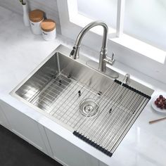 a stainless steel kitchen sink with grids on the front and bottom, next to a bowl of berries