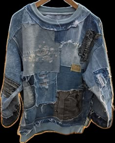 an old blue jean jacket hanging on a wooden hanger, with multiple patches and holes all over it