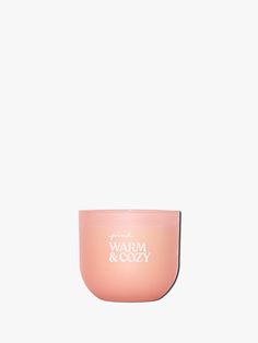 a pink candle with the words warm and cozy on it, against a white background