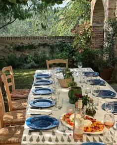 an outdoor table set with plates and glasses