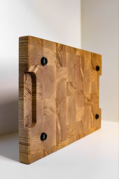 a wooden cutting board sitting on top of a white counter next to a knife holder