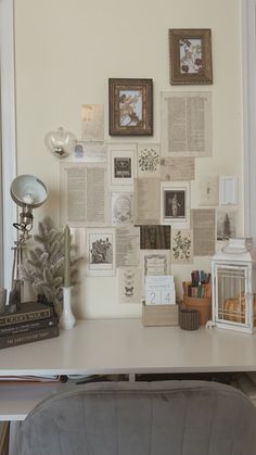 a white desk topped with lots of different types of books and pictures on the wall