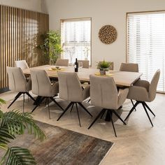 a dining room table with beige chairs and a potted plant in the corner on top of it