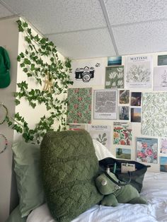 a bed with green pillows and pictures on the wall behind it in a dorm room