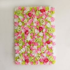 a square piece of art made out of flowers on a white surface with no one around it