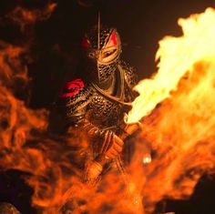 a man dressed in armor standing next to a fire