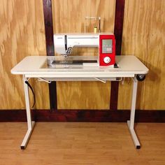 a sewing machine sitting on top of a white table next to a wooden paneled wall